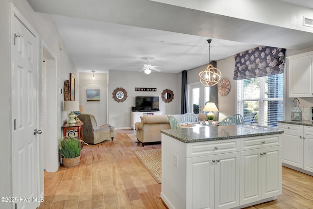 kitchen with white cabinetry, dark stone countertops, and decorative light fixtures