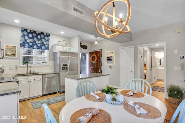 dining room with an inviting chandelier, sink, and light hardwood / wood-style floors