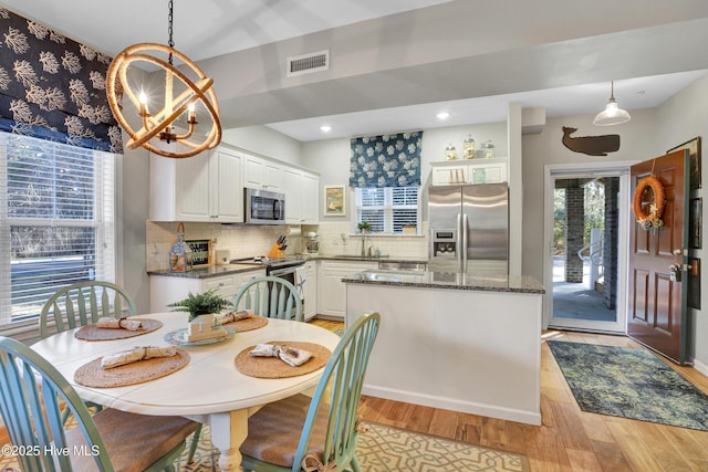 dining area featuring a wealth of natural light, a chandelier, and light wood-type flooring