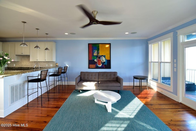 living room featuring sink, crown molding, dark wood-type flooring, and ceiling fan