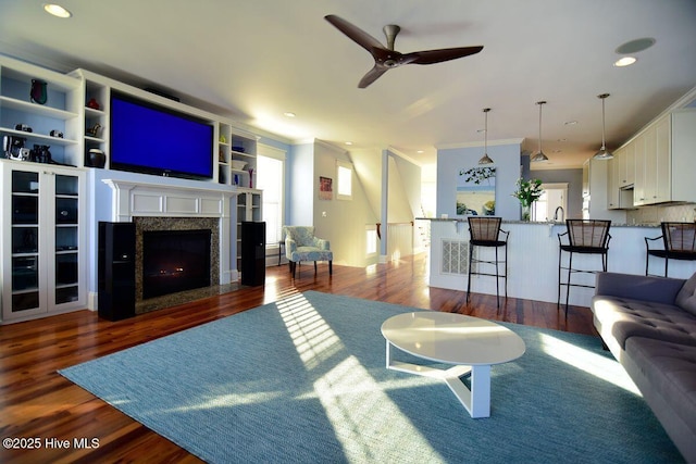 living room with crown molding, dark hardwood / wood-style floors, sink, and ceiling fan