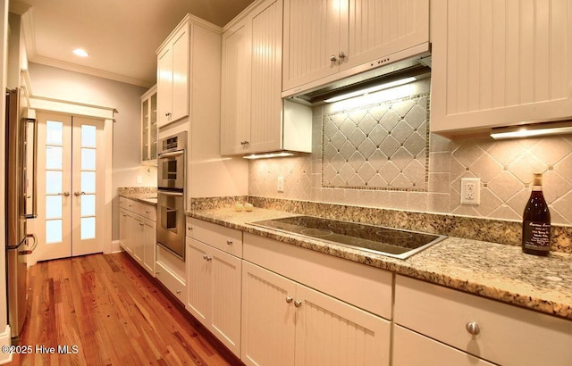 kitchen with french doors, light hardwood / wood-style flooring, appliances with stainless steel finishes, light stone countertops, and white cabinets