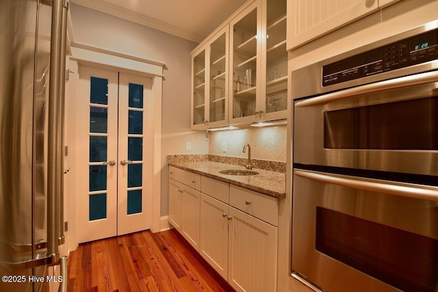 kitchen featuring french doors, sink, white cabinetry, crown molding, and stainless steel double oven