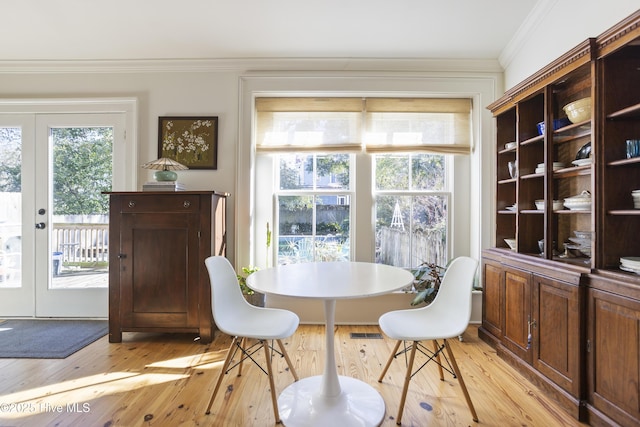 dining room with crown molding, french doors, and light wood-type flooring