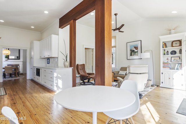 dining area featuring ornamental molding, lofted ceiling, and light wood-type flooring