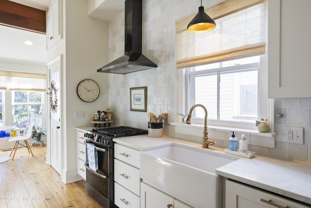 kitchen with range with two ovens, tasteful backsplash, white cabinets, and wall chimney exhaust hood