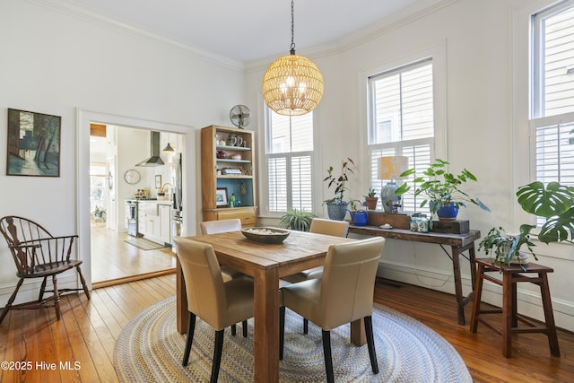 dining space featuring crown molding, baseboards, a notable chandelier, and light wood-style floors