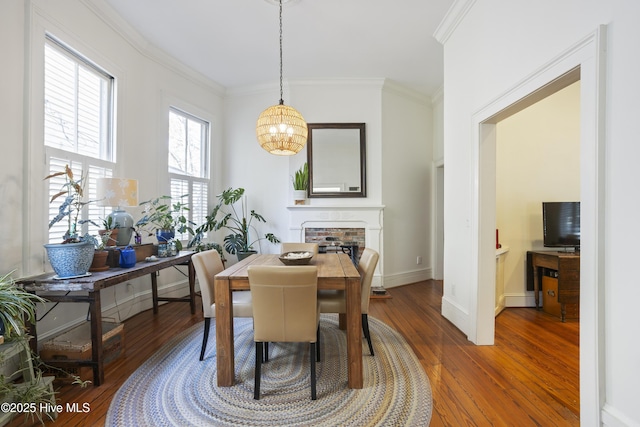 dining area with a fireplace, ornamental molding, dark hardwood / wood-style floors, and a chandelier