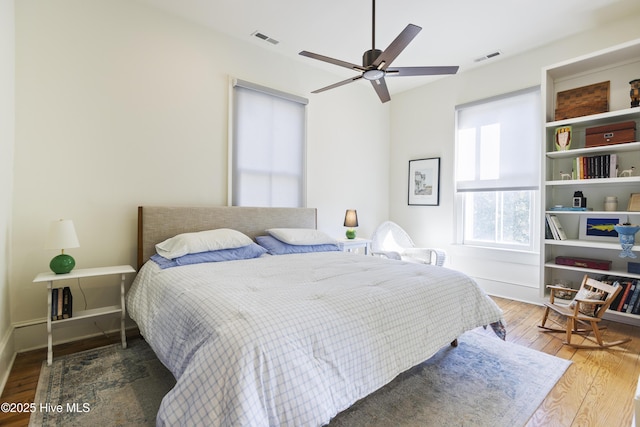 bedroom with visible vents, ceiling fan, baseboards, and wood finished floors