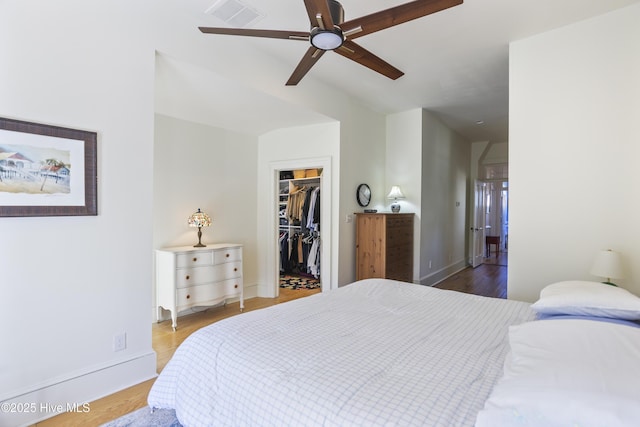 bedroom featuring ceiling fan, light wood-style flooring, visible vents, a closet, and a walk in closet