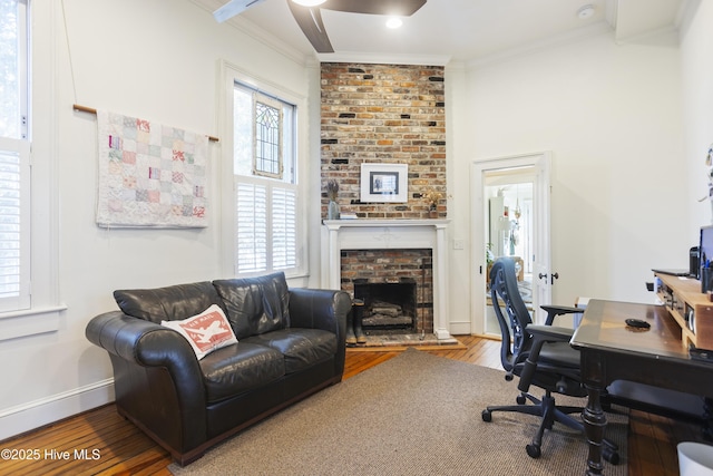 office space featuring hardwood / wood-style flooring, a healthy amount of sunlight, crown molding, and a brick fireplace