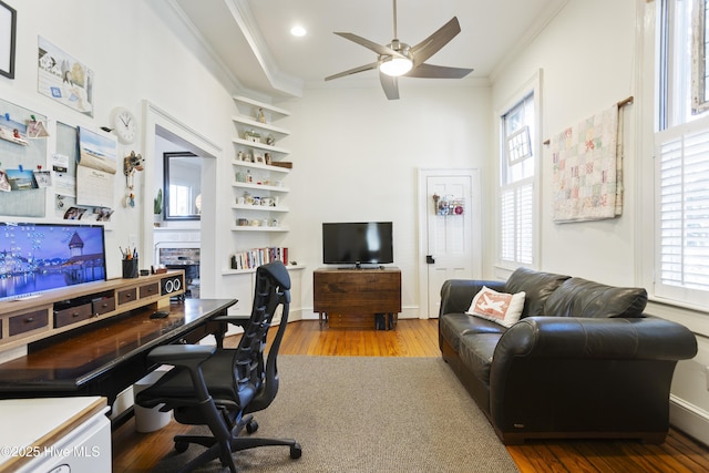 home office featuring ornamental molding, a ceiling fan, built in shelves, and wood finished floors