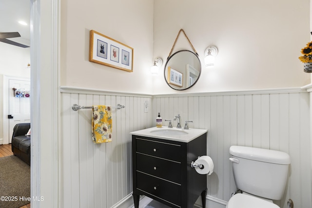 half bath featuring wainscoting, vanity, and toilet