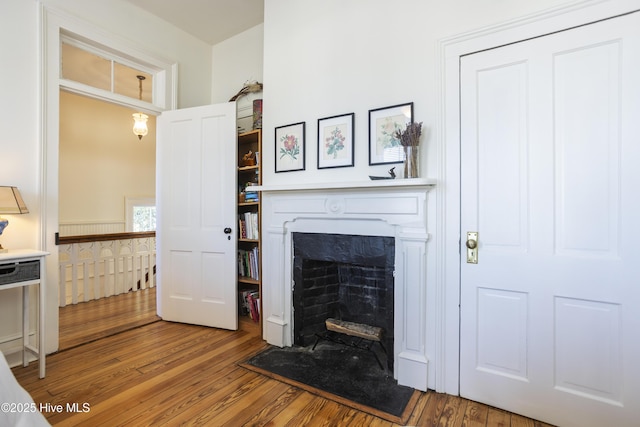 living area with a fireplace with flush hearth and wood finished floors