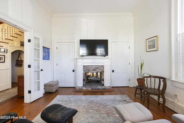 living room featuring a brick fireplace, crown molding, dark hardwood / wood-style floors, and french doors