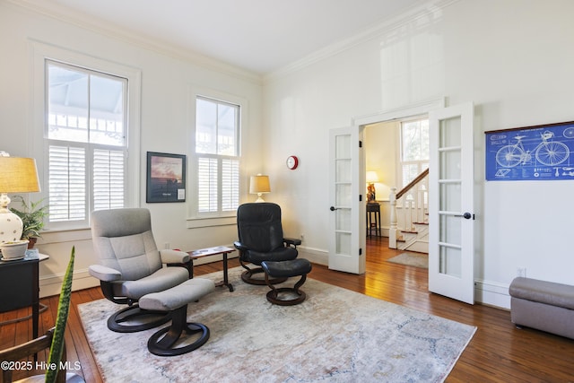 living area featuring wood-type flooring, ornamental molding, baseboards, and french doors