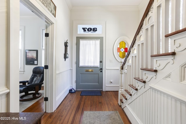 doorway with ornamental molding, wainscoting, and dark wood finished floors