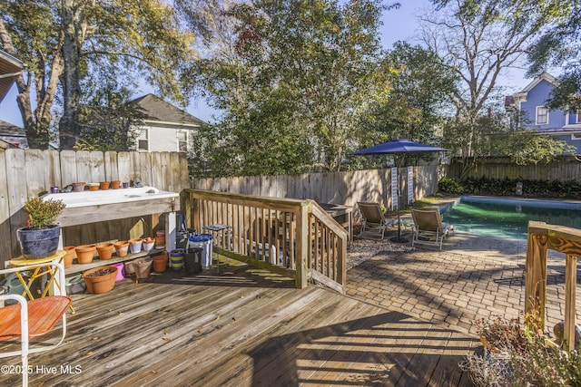 wooden terrace with a fenced in pool and a patio area