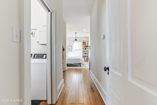 hall featuring wood-type flooring, washer / dryer, and baseboards