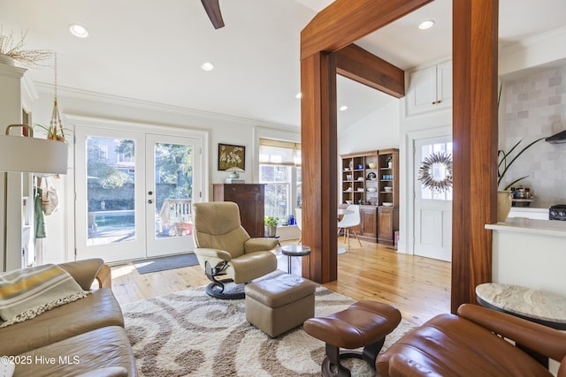 living room featuring ornamental molding, light hardwood / wood-style flooring, lofted ceiling with beams, and french doors