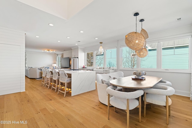 dining area featuring crown molding and light hardwood / wood-style flooring