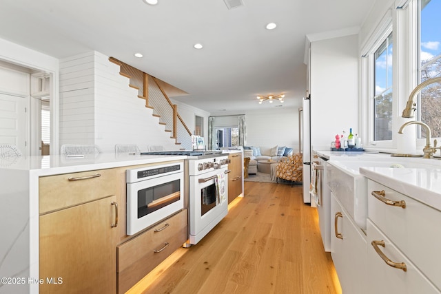 kitchen featuring light wood-type flooring, stainless steel refrigerator, ornamental molding, white cabinets, and high end white range