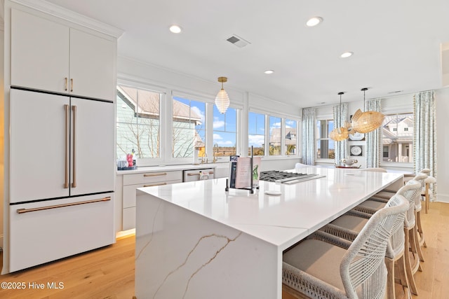 kitchen featuring a kitchen island, white cabinetry, pendant lighting, and white built in refrigerator