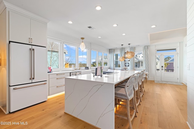 kitchen with a center island, decorative light fixtures, high end white refrigerator, and white cabinets