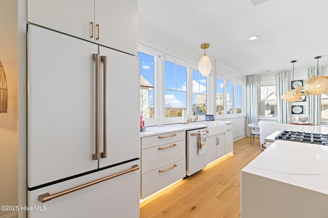 kitchen with white built in refrigerator, hanging light fixtures, white cabinetry, and dishwasher