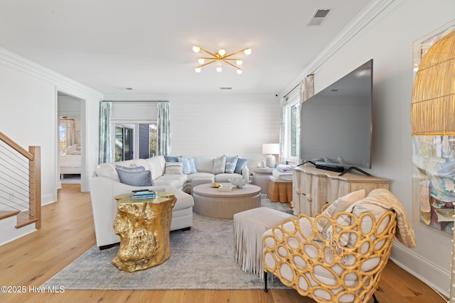 living room with an inviting chandelier, hardwood / wood-style flooring, and crown molding