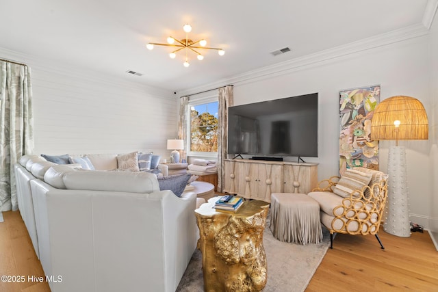 living room with ornamental molding, a chandelier, and light hardwood / wood-style floors