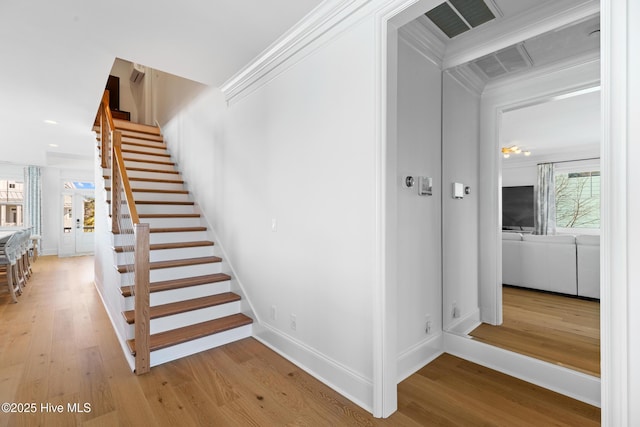 stairway with ornamental molding and hardwood / wood-style floors