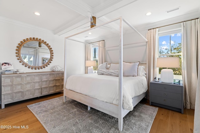 bedroom with beam ceiling, crown molding, and wood-type flooring