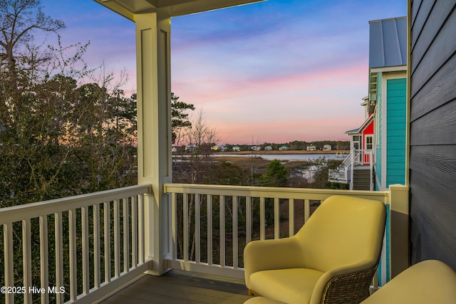 balcony at dusk featuring a water view