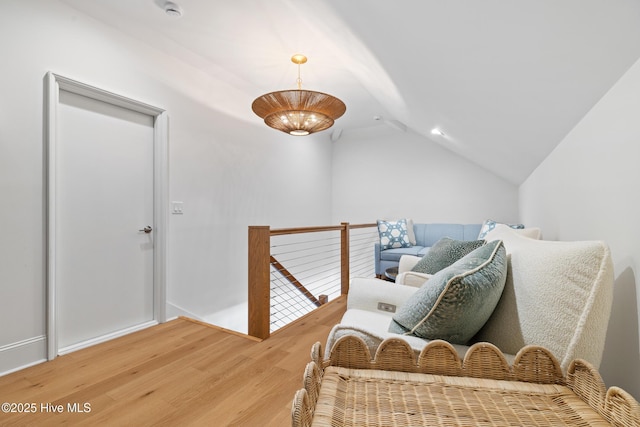 living area with hardwood / wood-style flooring, an inviting chandelier, and lofted ceiling