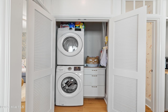 washroom with light hardwood / wood-style flooring and stacked washer / drying machine