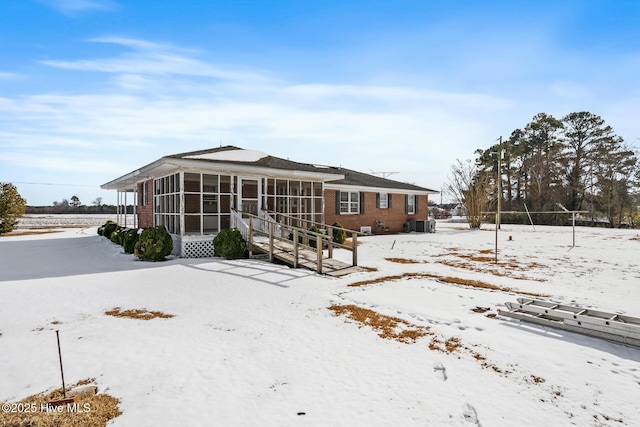 snow covered property with a sunroom