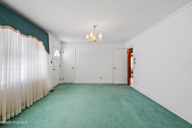 carpeted spare room featuring an inviting chandelier and crown molding