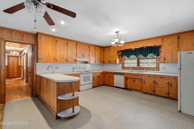 kitchen featuring sink, decorative light fixtures, kitchen peninsula, white appliances, and ceiling fan with notable chandelier