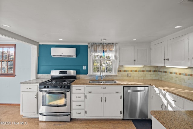 kitchen with sink, appliances with stainless steel finishes, white cabinetry, hanging light fixtures, and a wall mounted air conditioner