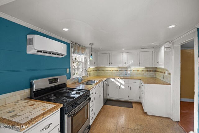 kitchen featuring crown molding, gas range, an AC wall unit, and white cabinets