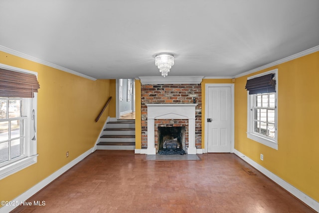 unfurnished living room featuring ornamental molding, a brick fireplace, and a chandelier