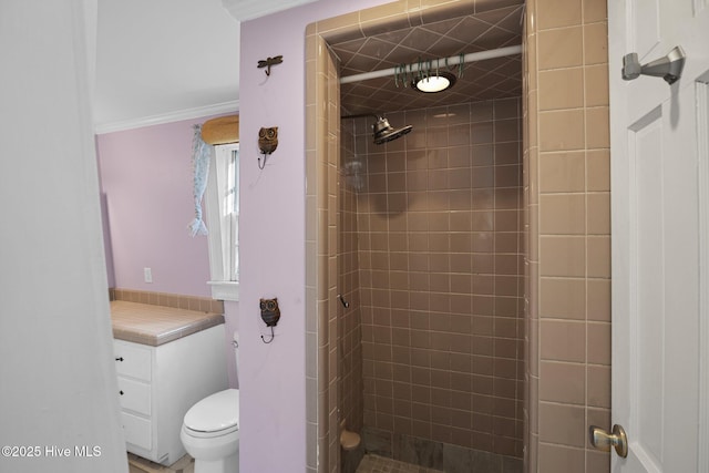 bathroom featuring crown molding, toilet, and tiled shower