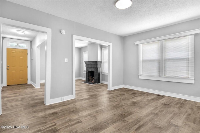 unfurnished living room featuring hardwood / wood-style flooring, a fireplace, and a textured ceiling