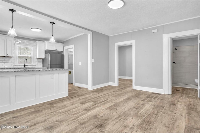 kitchen featuring stainless steel fridge, light stone countertops, white cabinets, and light hardwood / wood-style flooring