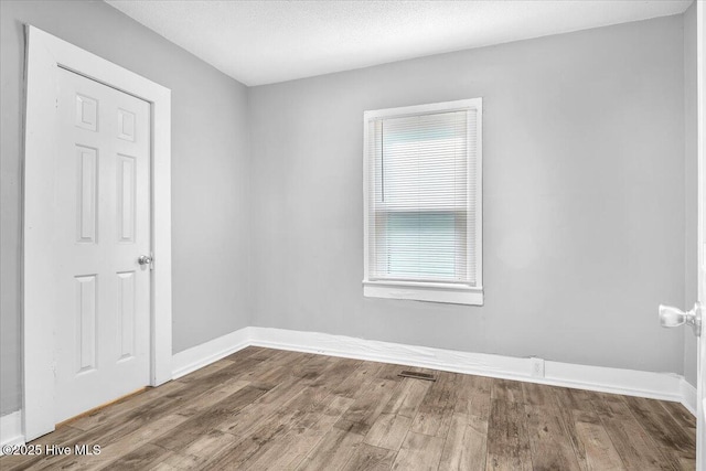 spare room featuring wood-type flooring and a textured ceiling