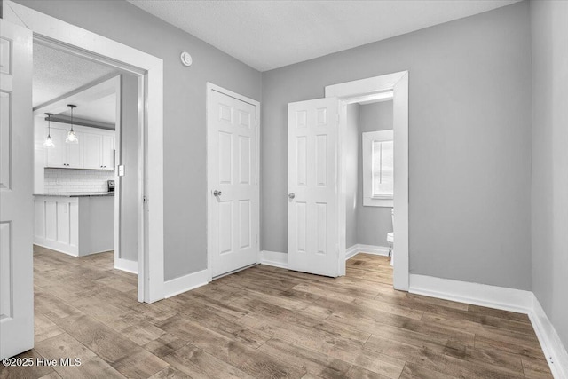 unfurnished bedroom with light hardwood / wood-style floors and a textured ceiling