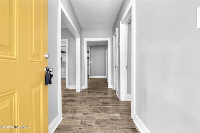 hallway featuring dark wood-type flooring and a textured ceiling