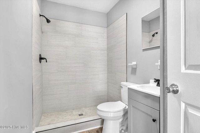 bathroom featuring vanity, a tile shower, and toilet