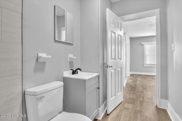 bathroom featuring wood-type flooring, toilet, a textured ceiling, and vanity